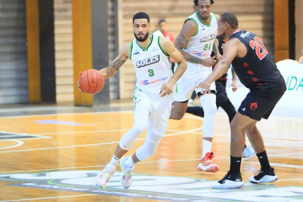 Anyeuri Castillo, de los Soles, avanza con el balón defendido por Leandro Cabrera, de los Leones. Al centro, Nigel Spikes.