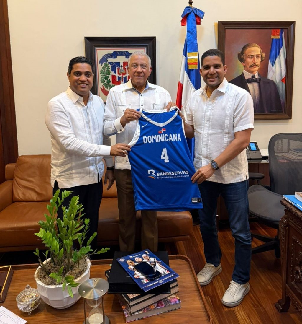 Andrés Bautista, ministro Administrativo de la Presidencia, recibe la chaqueta del equipo nacional de basket de Rafael Uribe y Kelvin Cruz.
