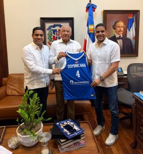 Andrés Bautista, ministro Administrativo de la Presidencia, recibe la chaqueta del equipo nacional de basket de Rafael Uribe y Kelvin Cruz.