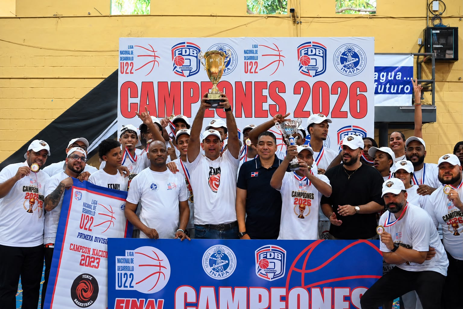 Jefry Espinal, gerente de Fénix, al centro, levanta la copa de campeón que le entregaron Junior Páez (Jipy) y José -Maíta- Mercedes.